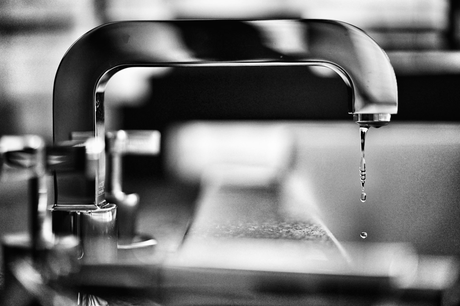 A chrome tap with a single drip of water