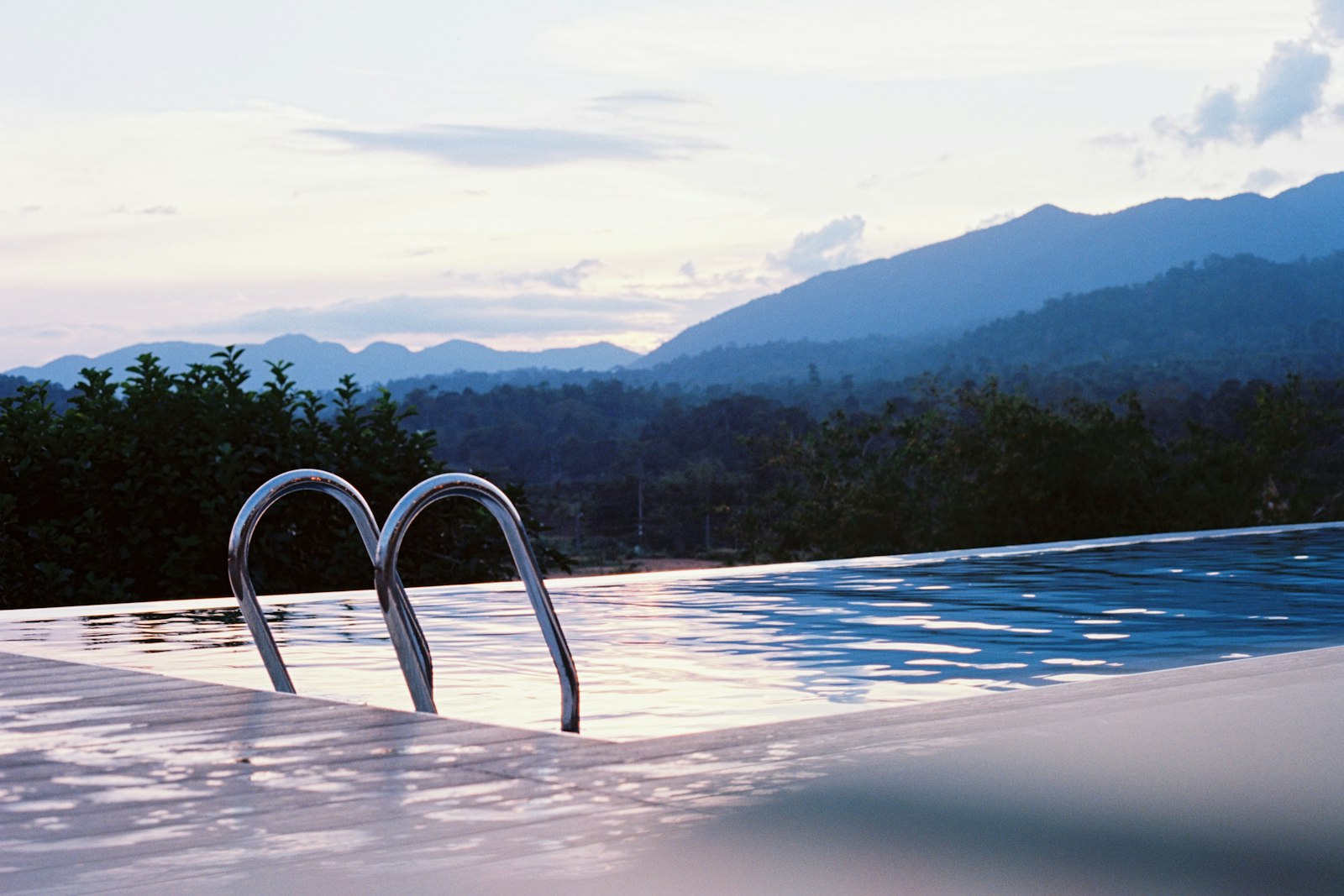 Infinity-edge pool at dusk overlooking the hills