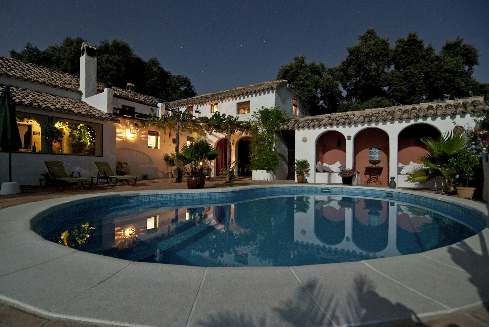 Courtyard pool glowing at twilight beside a villa